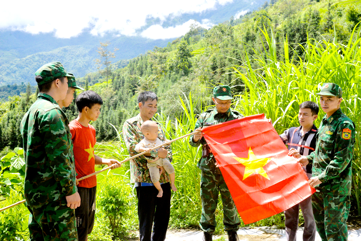 Chiến sỹ Đồn Biên phòng Cửa khẩu Quốc tế Thanh Thủy hướng dẫn người dân thôn Nặm Ngặt, xã Thanh Thủy treo cờ Tổ quốc.